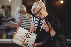 Happy brunette woman at the hairdresser selecting hair colours with her stylist
